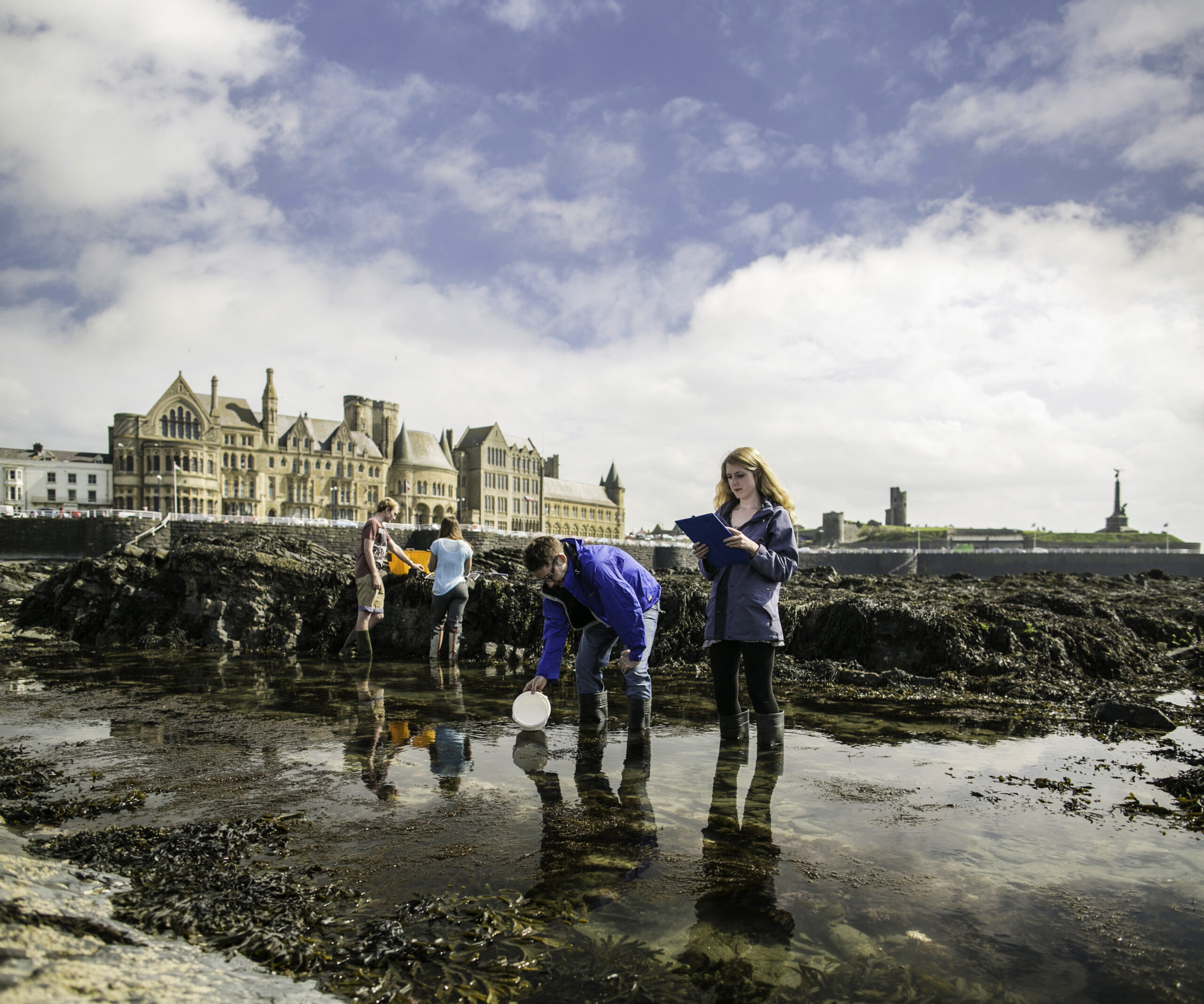 Young people on a beach with bucket and clipboard