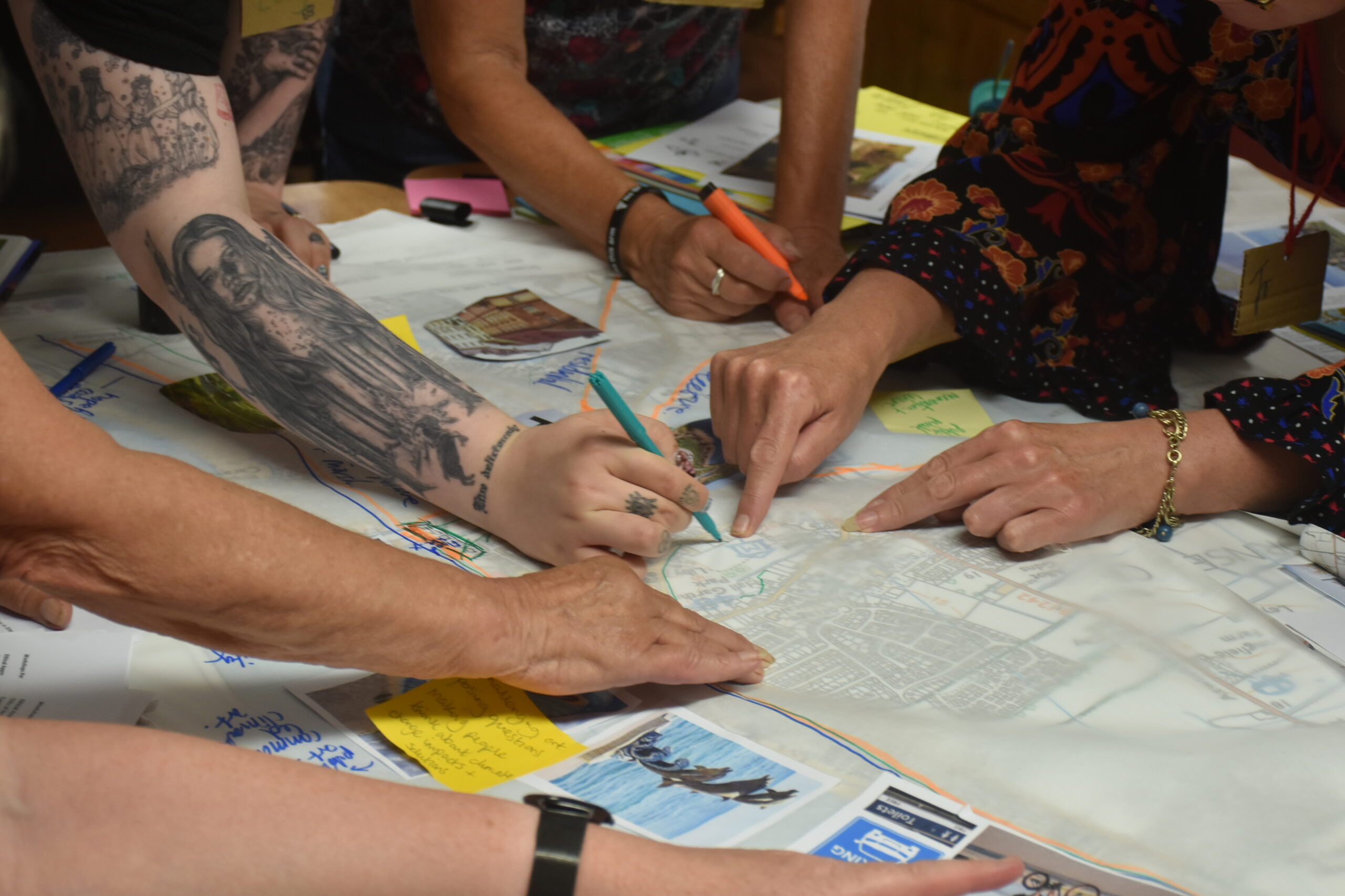 People at a workshop and there hands are showing drawing on text, maps and documents