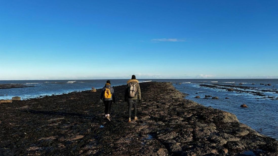 Two people walking along the coast at Robin Hoods Bay