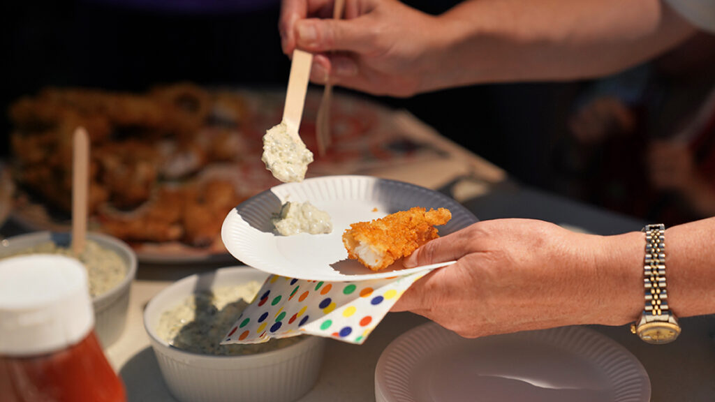 A close-up of a plate with part of a breaded fish portion which is about to be stabbed with a fork